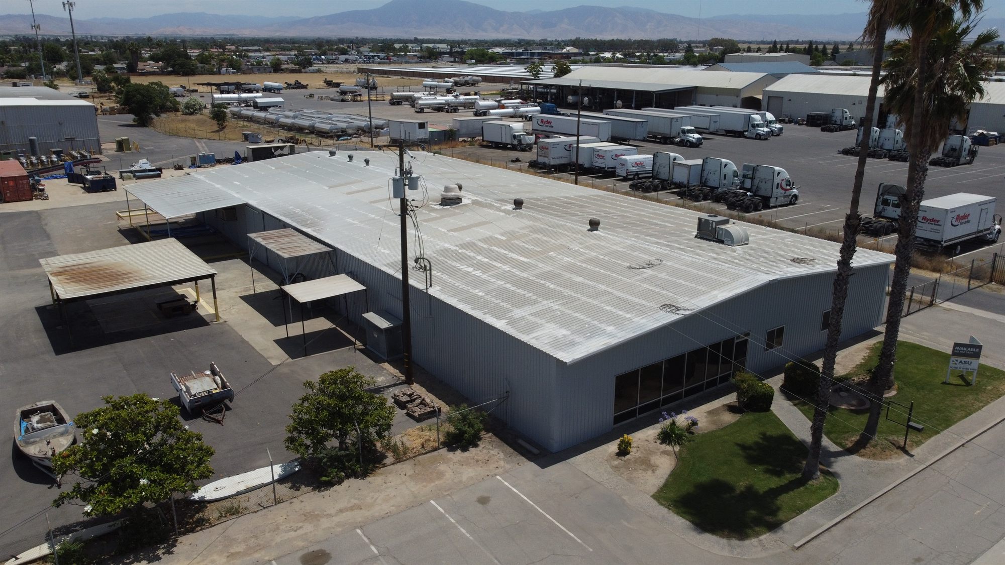 Oblique aerial of a metal industrial building with side canopies and a neighboring truck terminal