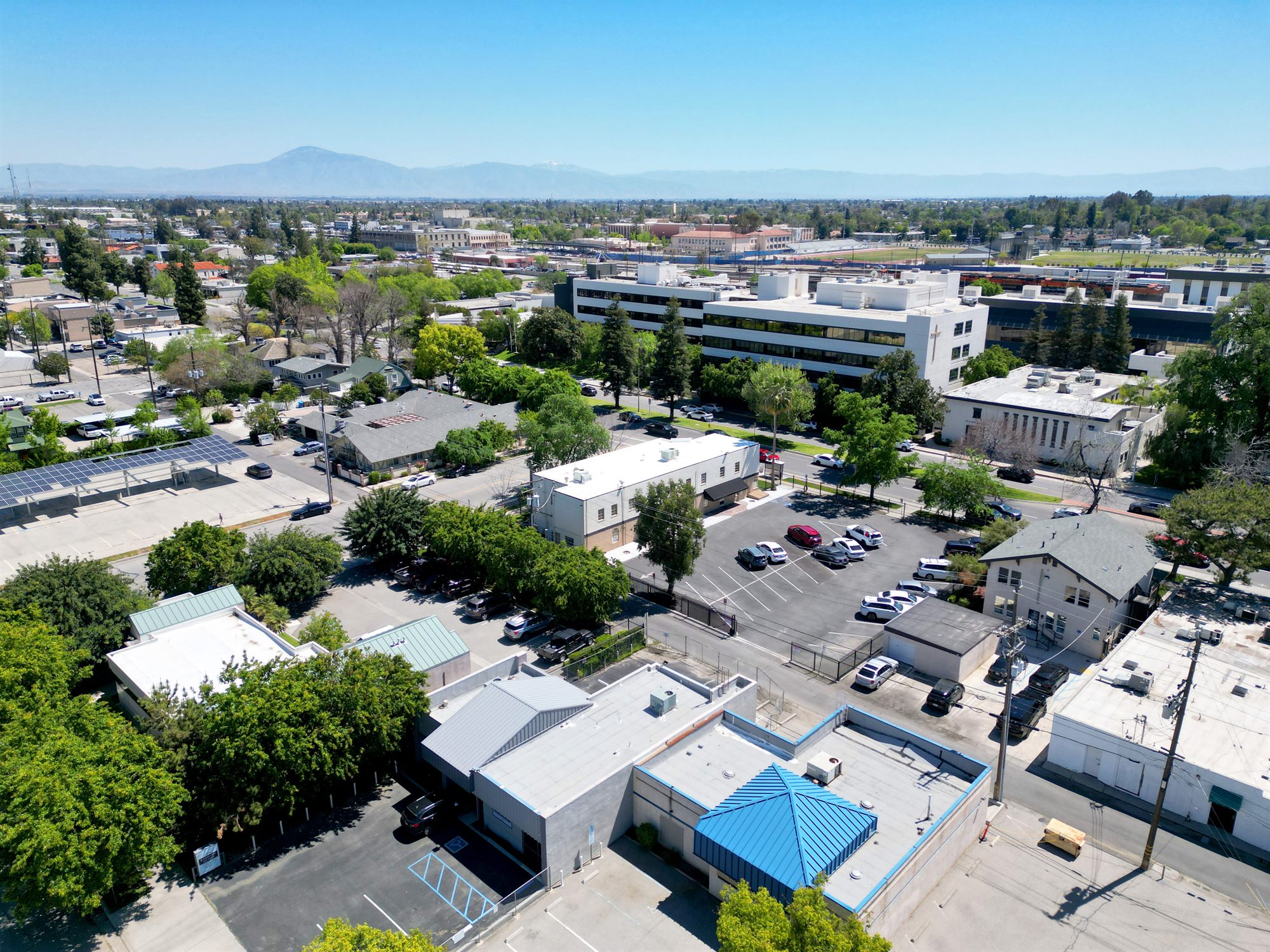 Aerial of a downtown area with office buildings, parking lots and distant mountains