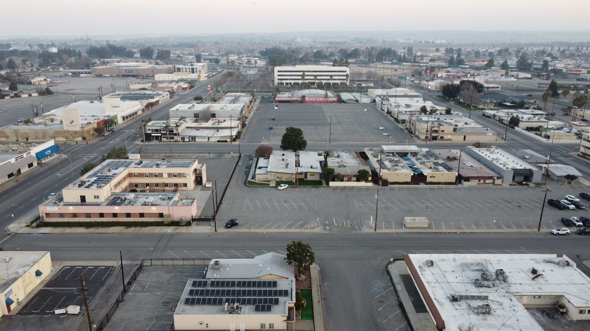 Aerial of a downtown block with offices, a large parking lot and a bowling alley