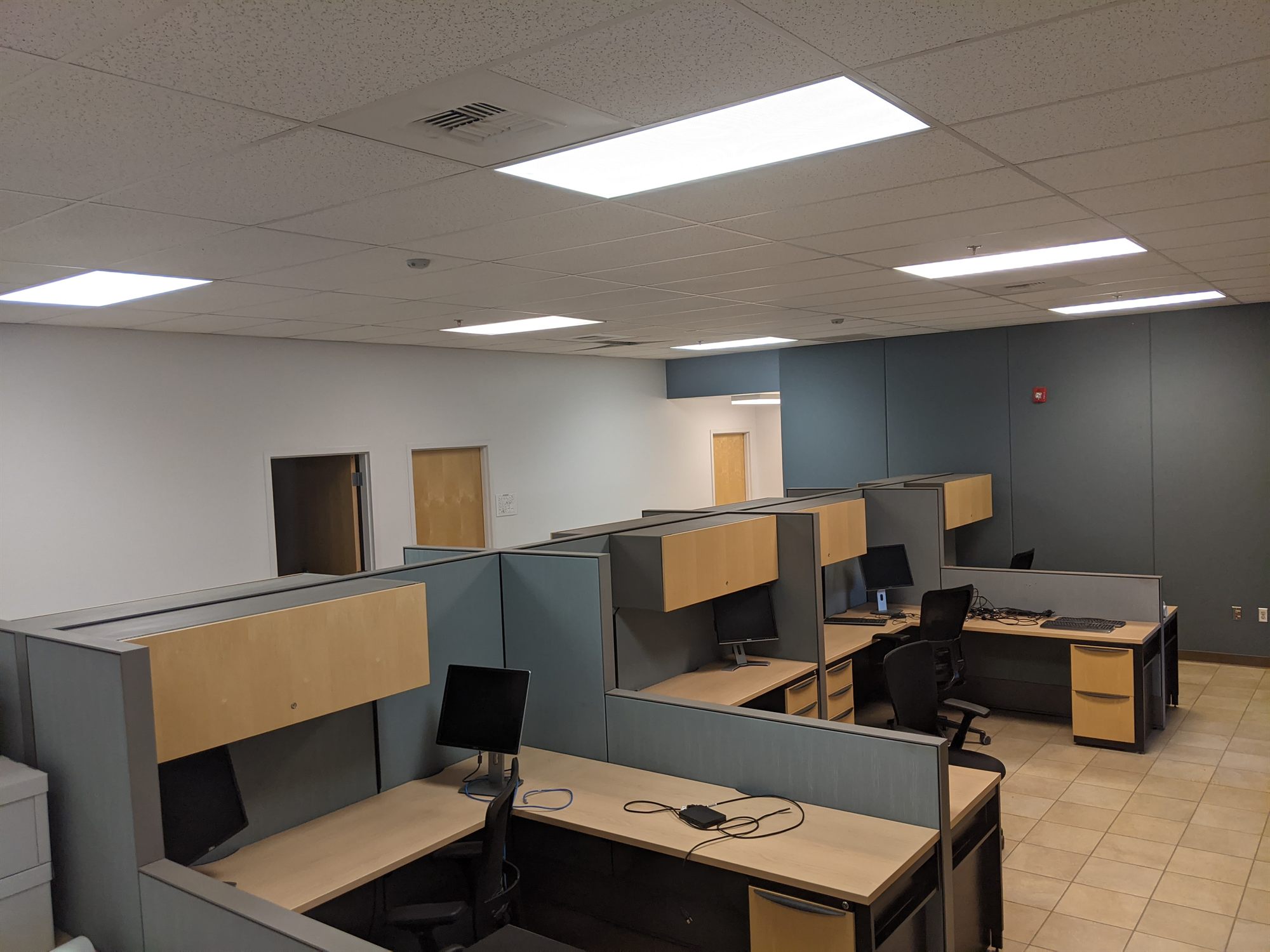 Open office area with grouped cubicles, desks and monitors