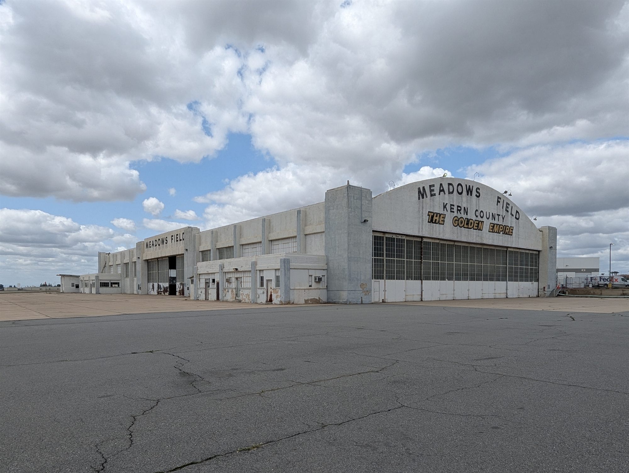 Historic white aircraft hangar with an arched roof sign at Meadows Field, Kern County, seen across the apron
