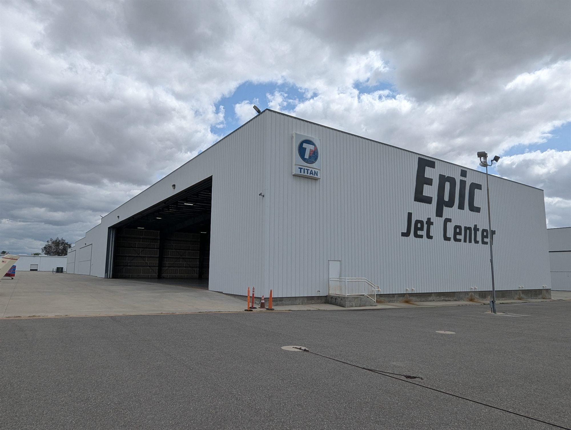 Corner of a large white metal aircraft hangar with an open bay door and a painted sign on the wall